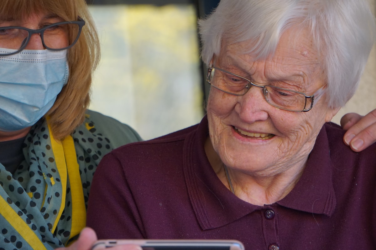 Caregiver helping a smiling senior resident use a tablet