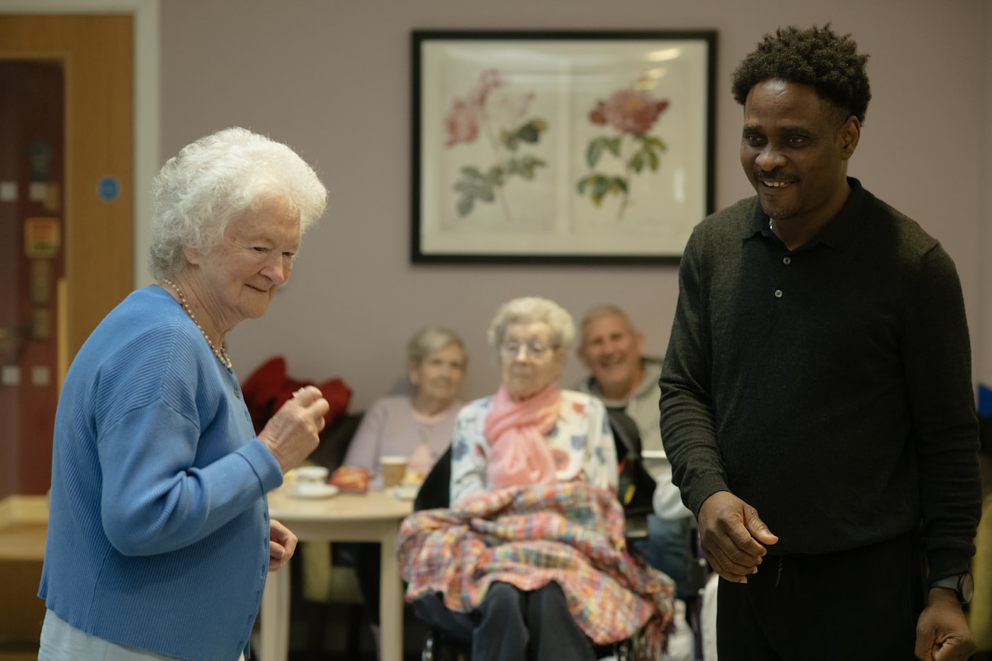A care team member sharing a laugh with residents in a nursing home common room